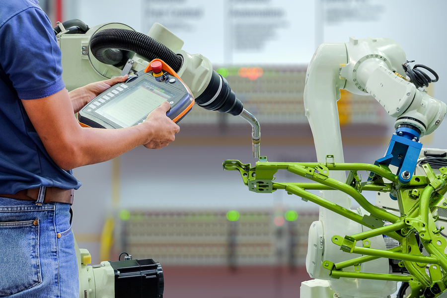 Engineers use a wireless remote control of robotic welding and robot workpiece for smart factory, industry 4.0 concept