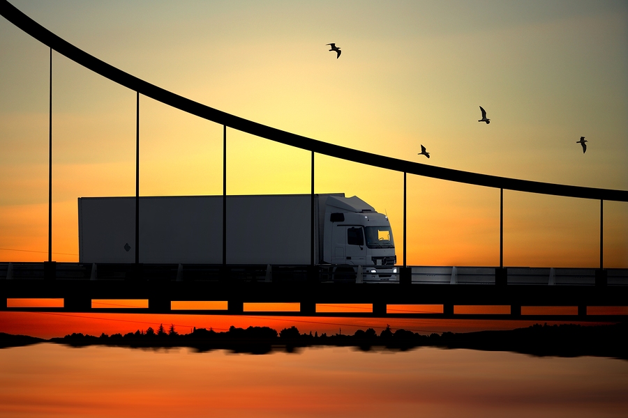 A truck travelling on a bridge in the sunset