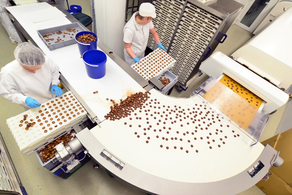 Two employees working a conveyer belt in a food manufacturing plant