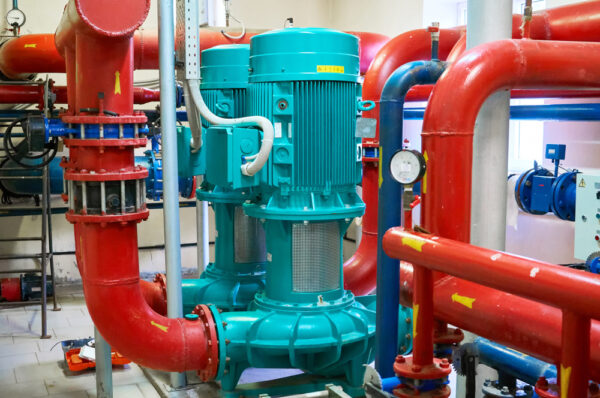 Two Vertical Engine Painted Blue With Pumps Connected To Pipes
