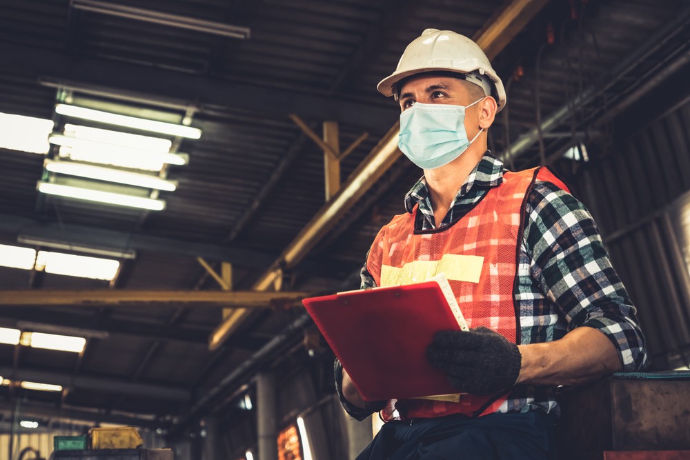 Factory worker with a protective mask and clipboard