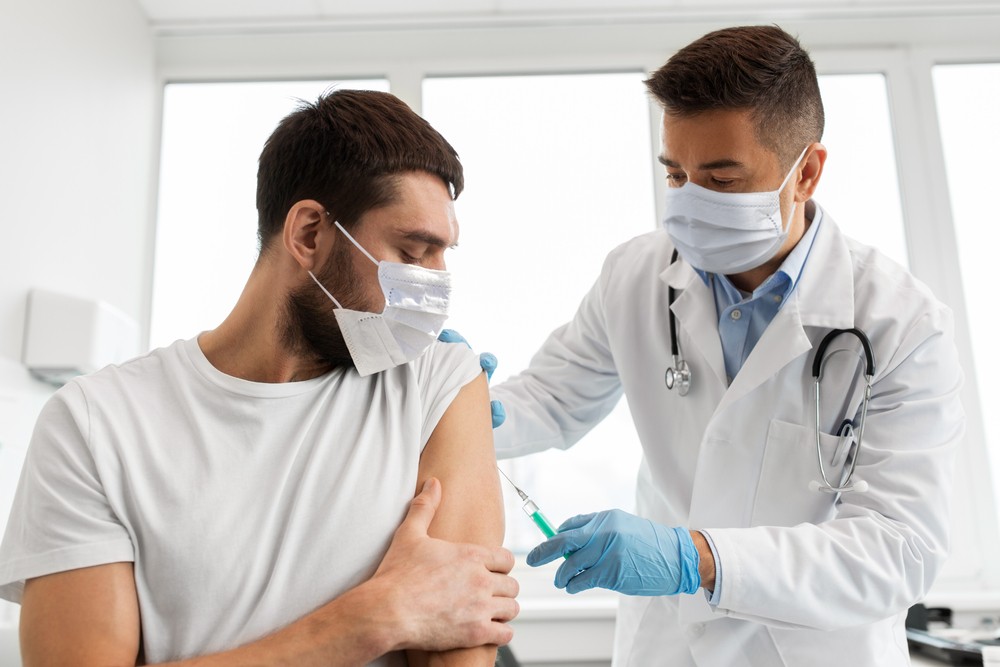 A doctor giving a man a vaccine in a doctors office