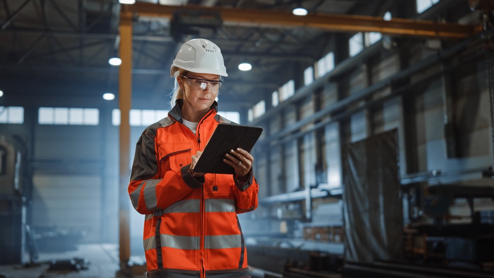 An engineer in a factory looking down at an iPad