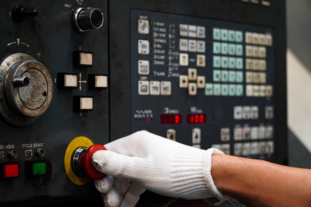 Worker pushing red power button on control panel