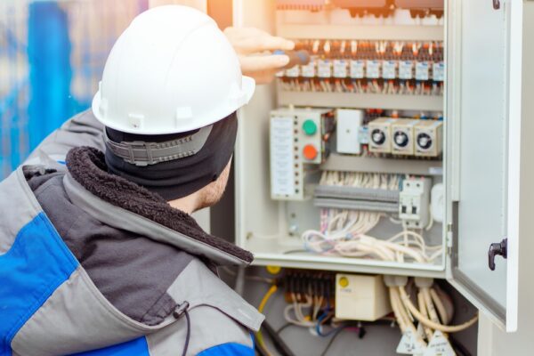 Professional Electrician Connects Wires In Electrical Panel Room