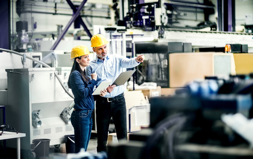 Two Project Managers Standing In Modern Industrial Factory