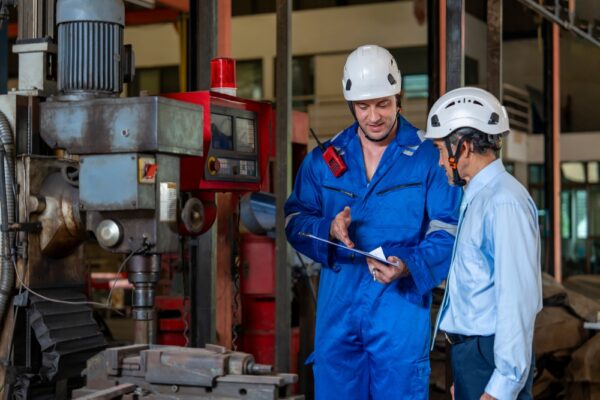 Workers inspect factory machinery