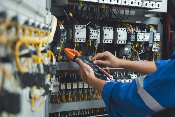 Electrician Measures With Multimeter In Control Panel