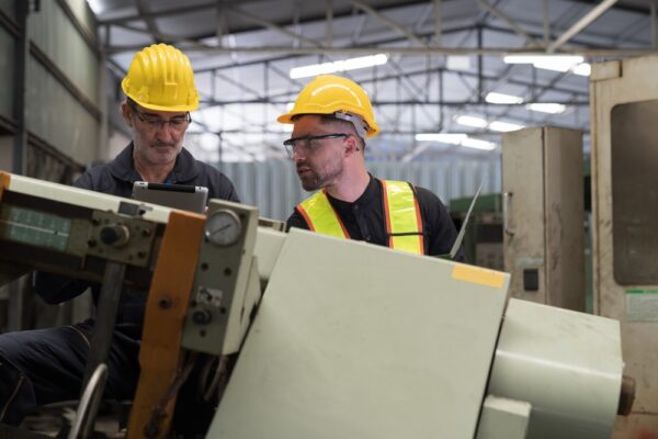 Two Engineers Checking CNC Machine In Factory