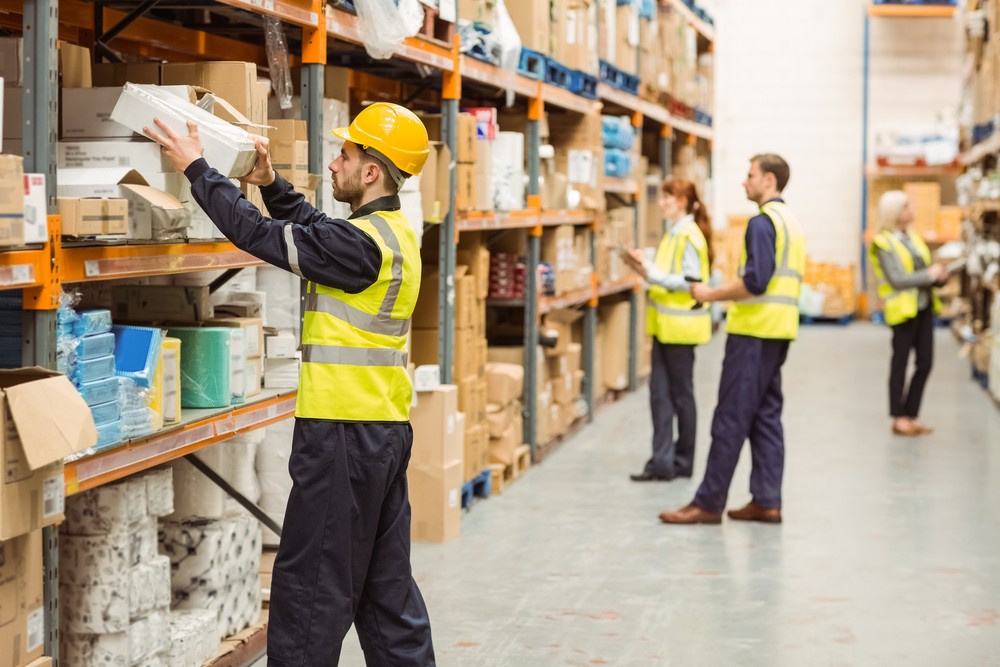 Three employees pulling products off a shelf in a warehouse