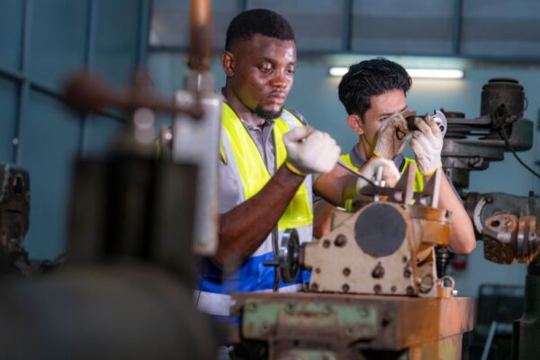 Two Engineers Focus On Adjusting Industrial Machinery With Precision. Teamwork