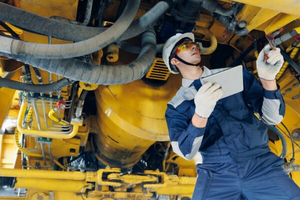 Engineer Examining Mining Machinery With Tablet