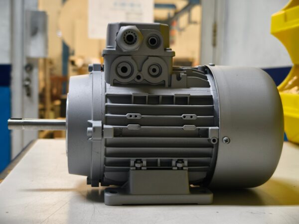 A Robust Grey Industrial Electric Motor Sits On A Workbench
