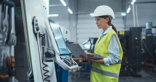 Machinery Technician Using Laptop Computer and Programming a CNC