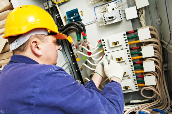 Electrician Builder At Work With Tester Measuring High Voltage