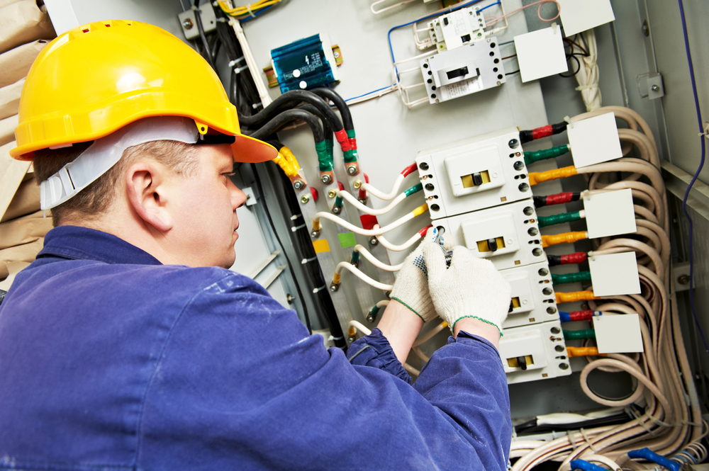 Electrician Builder At Work With Tester Measuring High Voltage