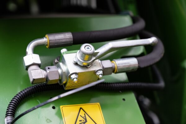 Close-up Of Hydraulic Valve System On Green Machinery.