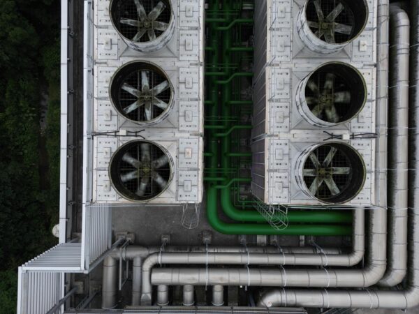 Top Down View Of Industrial Cooling Towers And Green Pipelines.