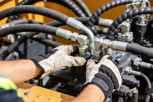 Close-up Of A Worker's Gloved Hands Manipulating Intricate Hydraulic Components