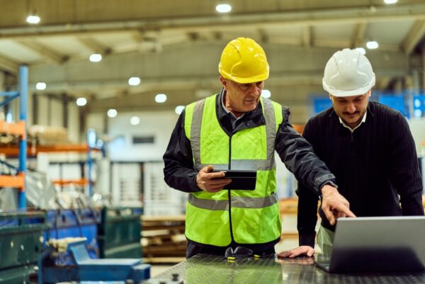 Two Factory Supervisors In Hard Hats And High-visibility Vests
