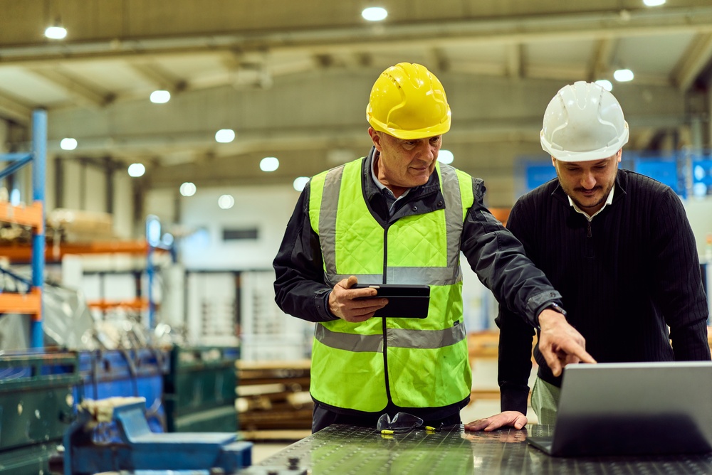 Two Factory Supervisors In Hard Hats And High-visibility Vests