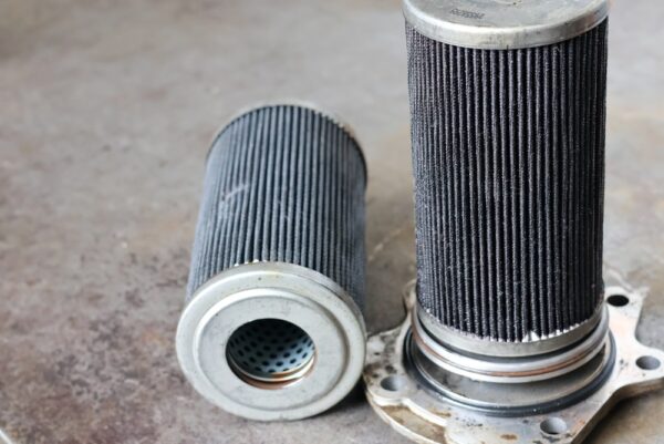 A Close-up Photograph Shows Two Dirty Used Industrial Fluid Filter
