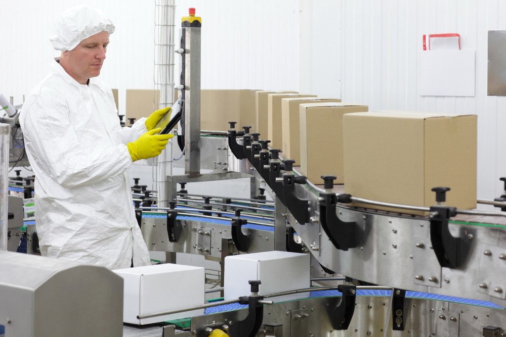 An engineer monitoring a product line of boxes