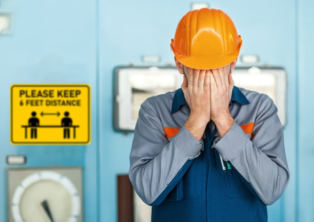 Factory Worker face-palms in front of social distancing sign