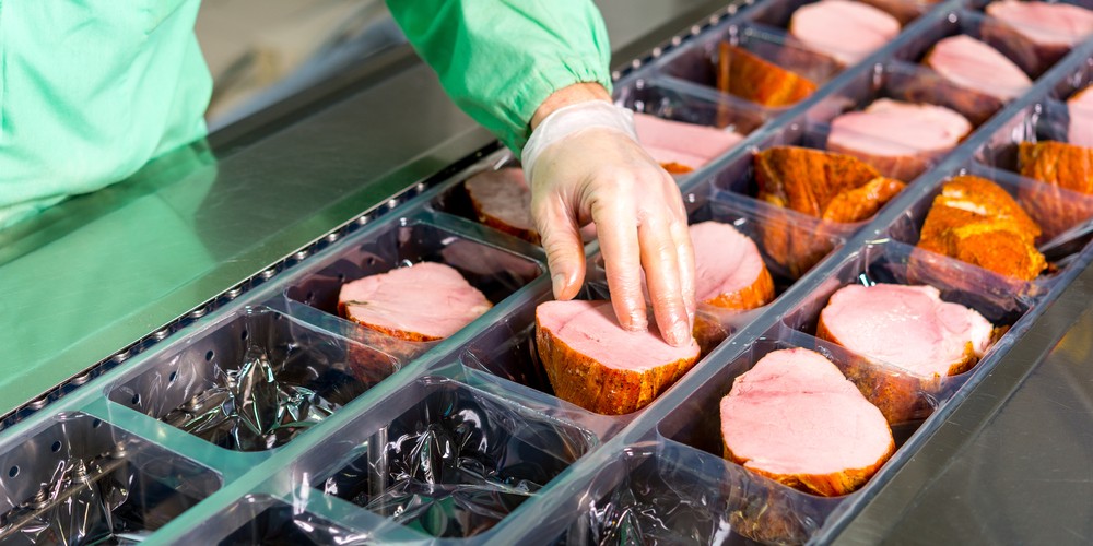 An employee packing meat in a food manufacturing facility