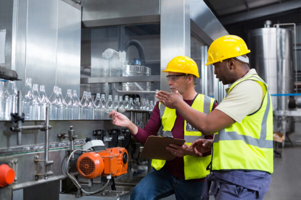 Two Factory Workers Discussing While Monitoring Drinks Production Line