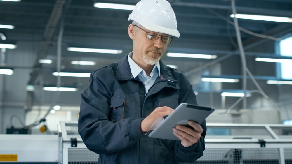 Man in manufacturing facility looking at an iPad