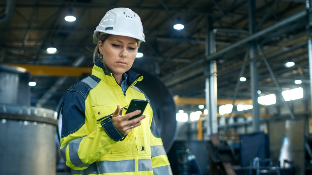 An engineer in a warehouse looking at a phone
