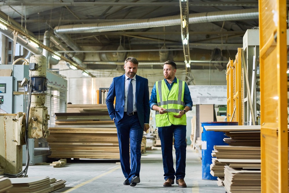 Man in suit and factory worker walking in a factory