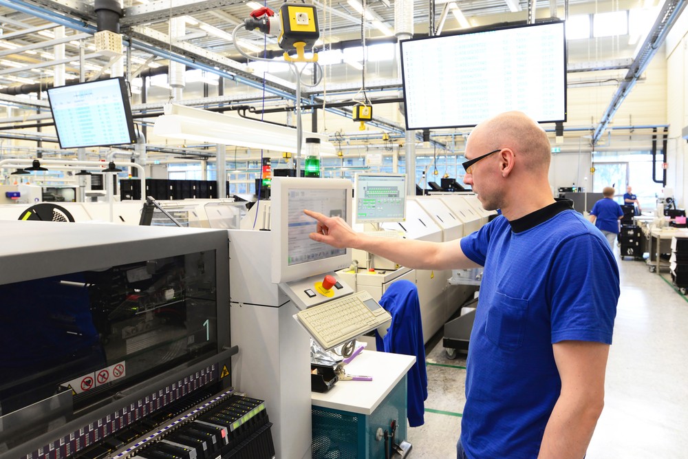 An engineer pointing at a computer in a factory
